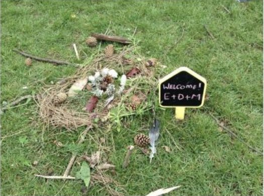 A nest made from sticks and feathers with a Welcome sign